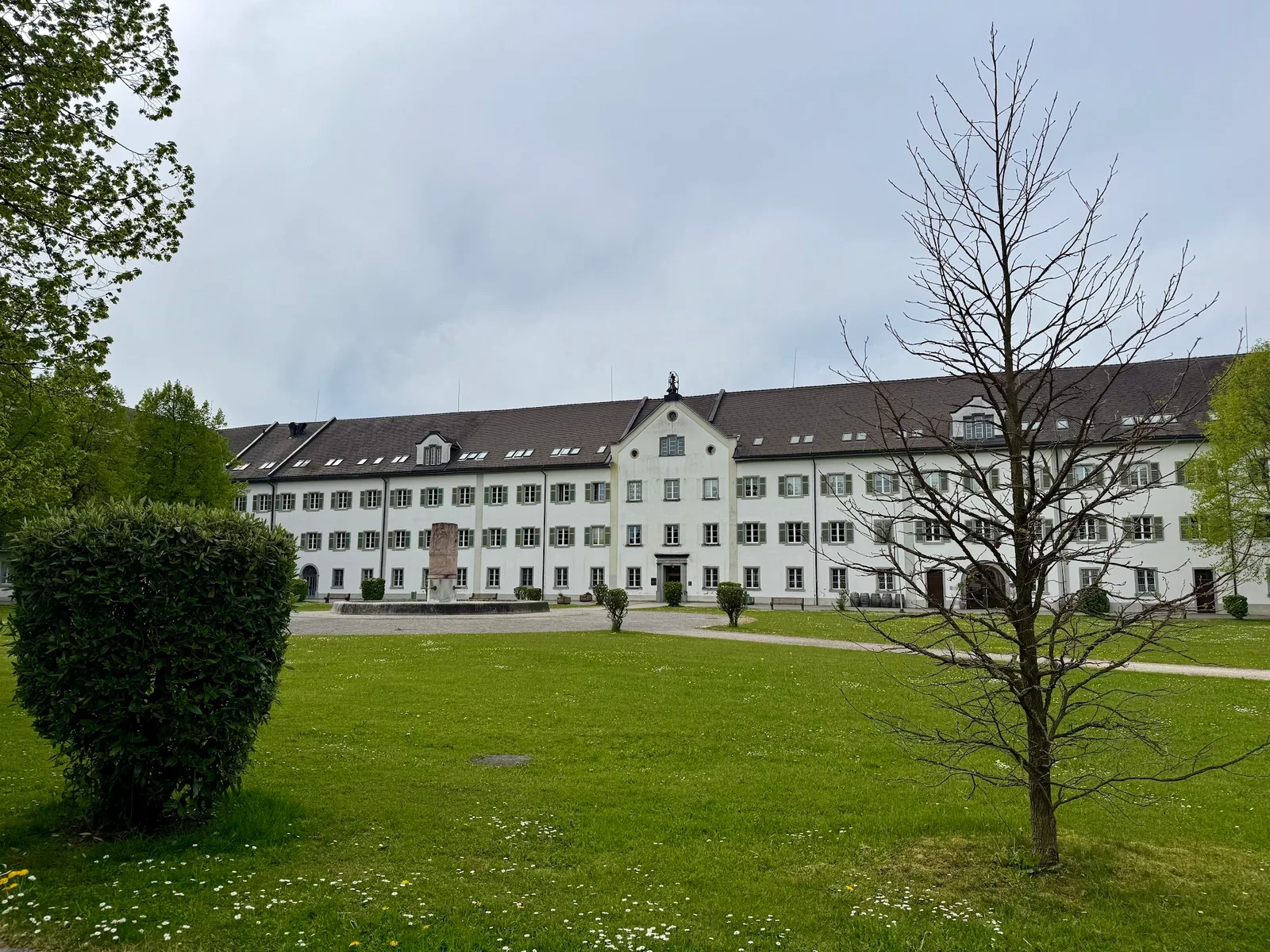 Das langgestreckte Klostergebäude Mehrerau mit Grünfläche und Bäumen davor